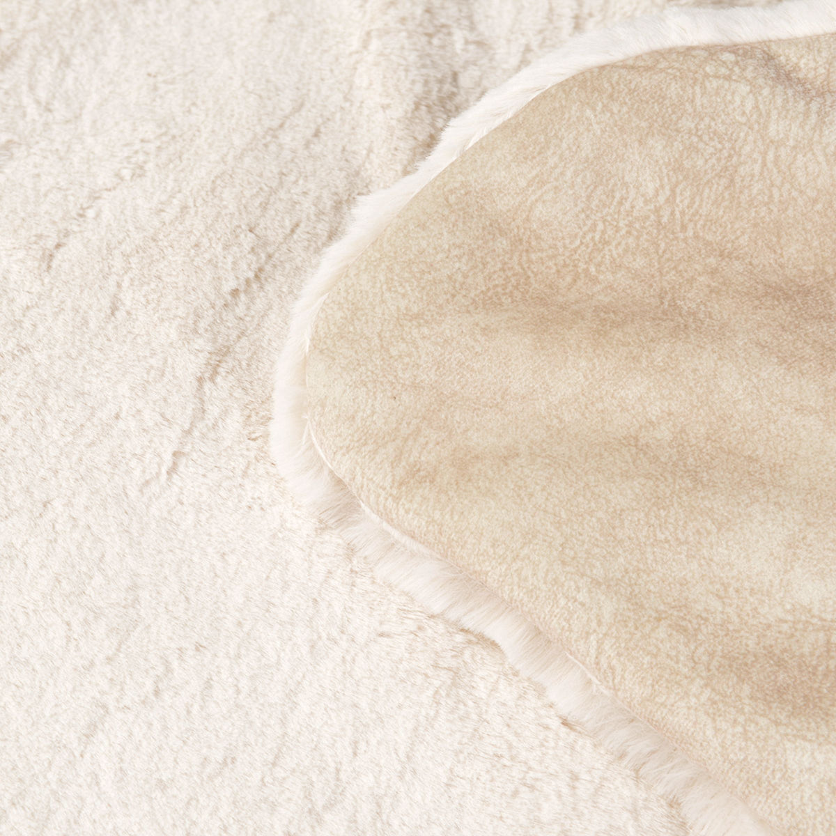 Detailaufnahme der zwei Seiten der cremeweißen Hundedecke Hyggelamb mit flauschigem Lammfell-Imitat und beiger Sommerseite